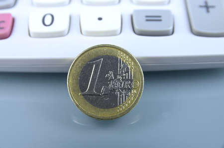 One euro coin against calculator on grey backgroundの写真素材