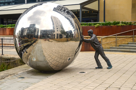 Monument as a Man pushing a huge  silver ball in Leeds Dockのeditorial素材