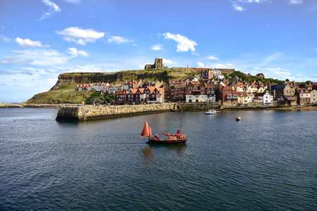 View of boat returning to Whitby Harbour and gothic church in backgroundのeditorial素材