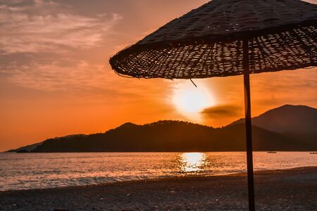 Sea side beach sunset and umbrella silhouette.の写真素材