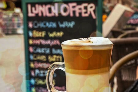 Cup of cappuccino against  menu board in restaurant