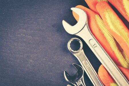 The different forms of screws and a wrench with nuts and gloves, with vignette effect