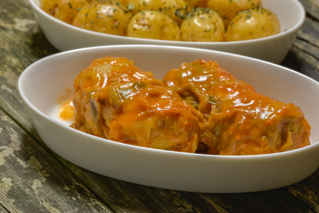 Traditional homemade polish style stuffed cabbage rolls  with meat and rice, topped with tomato based sauce and new potatoの写真素材