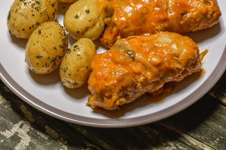 Traditional homemade polish style stuffed cabbage rolls  with meat and rice, topped with tomato based sauce and new potatoの写真素材