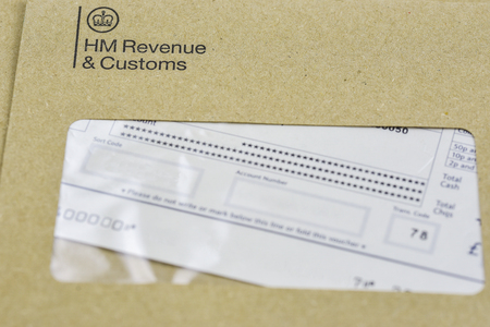 England, UK - August 16 2018: The logo of Her Majestys Revenue and Customs on envelope, with money or check included inside.  HMRC is a non-ministerial dept of the UK Government.のeditorial素材