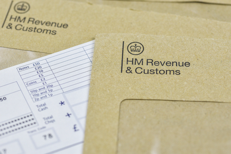 England, UK - August 16 2018: The logo of Her Majestys Revenue and Customs on envelope, with money or check included inside.  HMRC is a non-ministerial dept of the UK Government.のeditorial素材