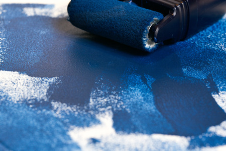 Painted surface and painting supplies:  mini roller, blue paintの写真素材