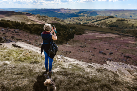 A woman taking a photo with her phone of amazing mountains landscape.の写真素材