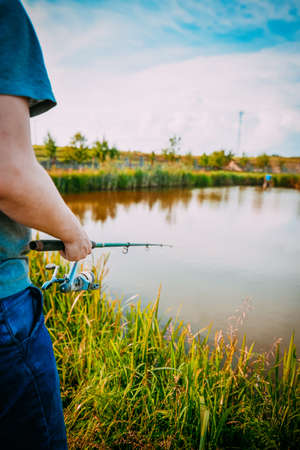 Young man fishing on lake at sunset enjoying hobby. Outdoor, activity. Narrow focus.