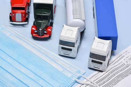 Four lorry toys, and face mask in concept about transport departament against coronavirus pandemic.