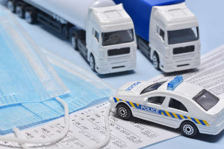 Two lorry toys stopped by police, and face mask in concept about transport departament against coronavirus pandemic.の写真素材