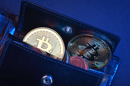 Black leather wallet and bitcoins isolated on black backgroundの写真素材