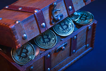 Wooden treasure chest with valuables, bitcoins, pennies or dollars isolated over dark backgroundの写真素材