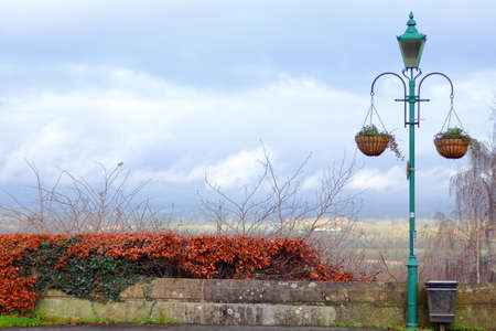 Street lantern with hanging baskets with the stormy clouds over the valley in the backgroundの写真素材