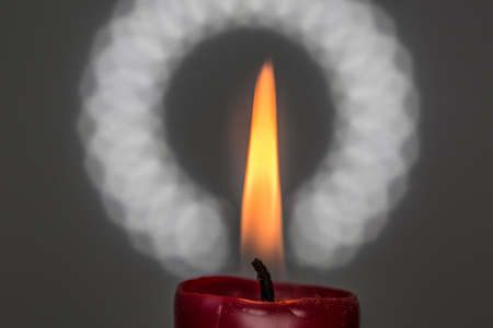 red candle burns with yellow flameの写真素材