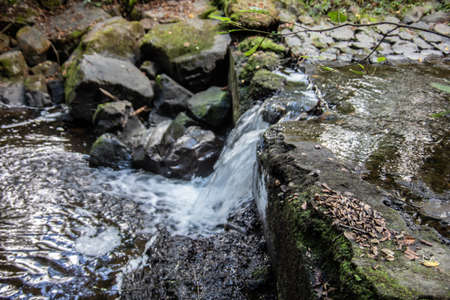 River course littered with rocks with waterfall in Siegerlandの写真素材