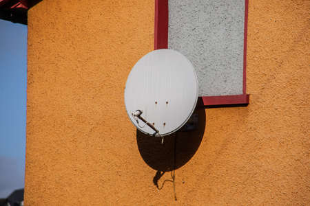 Satellite dish on orange house wallの写真素材