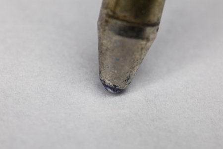 Ballpoint pen refill with ink ball writes on paper very close up
