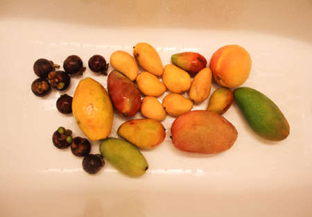 Many fresh and wet mangos on  a white background