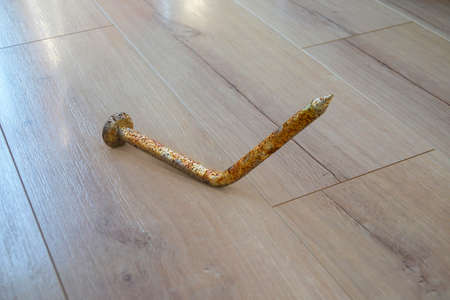 Tetanus awareness. Rusty old bent metal nail on the floor, 3D illustration. Old nails and other dirty objects are potential source of tetanus bacteria transmitted by infected woundsの写真素材