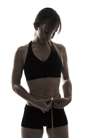 one beautiful fitness woman  fitness sport measuring her waist silhouette on white backgroundの写真素材