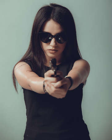 Shot of a military woman posing with guns, black glasses in the eyesの写真素材