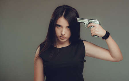 Young woman at despair holding a gun to her headの写真素材
