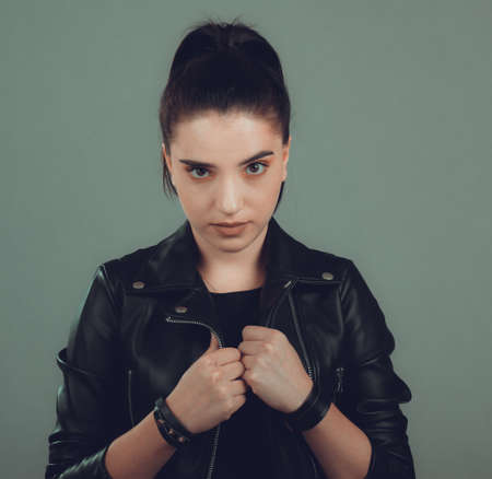 Portrait of young beautiful woman with black leather jacket ,on grey backgroundの写真素材