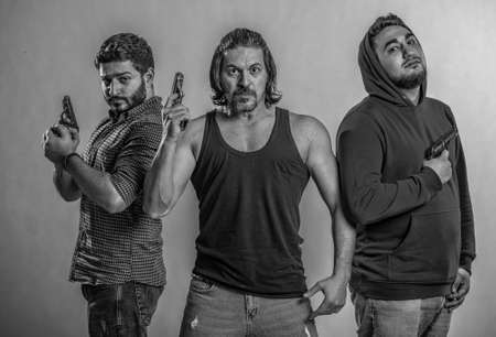 weapons in the hands of three gangster men,they look at the angry camera,dressed in a black T-shirt...