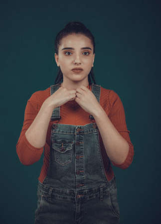 beautiful girl model in a red sweater and blue overalls posingの写真素材