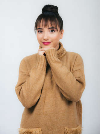 portrait of a beautiful young girl in a brown warm sweater isolated on white background,looking at camera smilingの写真素材