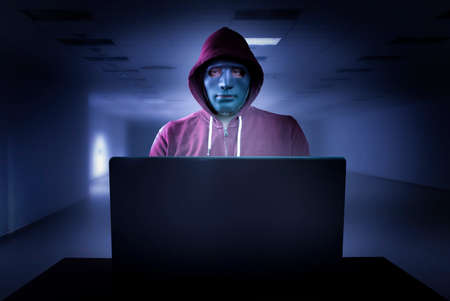 Hacker with mask in front of a laptopの写真素材