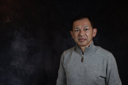 Middle-aged Japanese man in gray turtleneck wool sweater. Concept image of Warm Biz, stability in...