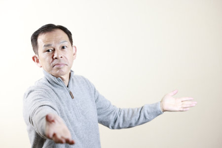 Middle-aged Japanese man in gray turtleneck wool sweater under white background. Concept image of Warm Biz, stability in daily life, and sustainable living.の写真素材
