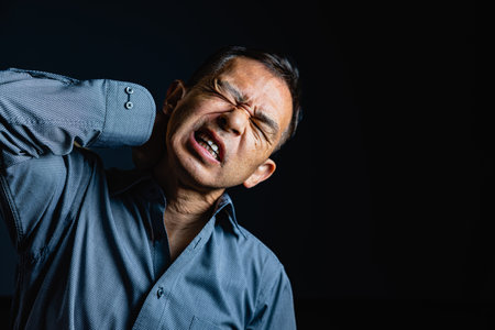 Middle-aged Japanese man in gray casual Y-shirt on dark background. Conceptual image of world peace, stability in daily life, and sustainable living.の写真素材