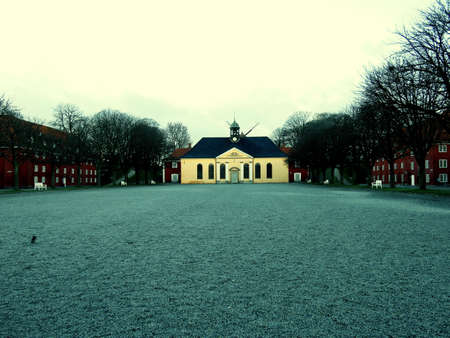 Eerie yellow house surrounded by red brick houses in copenhagen denmarkの写真素材