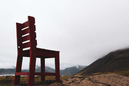 Famous large red chair atop a rocky hill facing the foggy mountains of Iceland along the Golden Circle.の写真素材