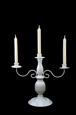 white candlestick with three burning white candles in front of black backgroundの写真素材