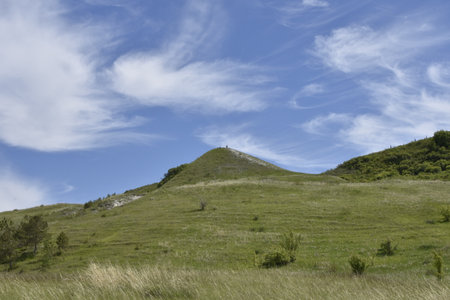 A grassy hillside under a blue sky studded with clouds near Ulyanovsk, Russiaの写真素材