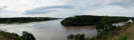 Panoromic Iguazu waterfalls in Argentina, Panoramic view of many majestic powerful water cascades with mist and reflection of blue sky with clouds. misty air in the foregroundの写真素材