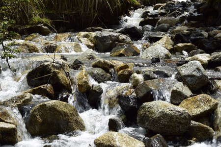 A stormy mountain river flows through the rocks, on the way to Lagoon 69. Huascaran National Park in...