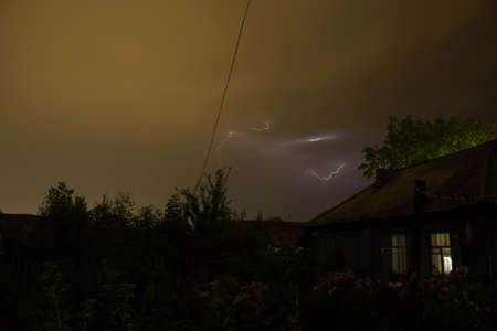 Thunderbolt (Lightning) over the house and dark stormy sky on the background.の写真素材