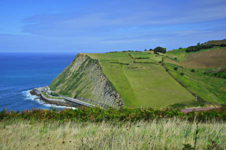 View of the road along the ocean and green hills. The Northern Way of St. James, Spain.