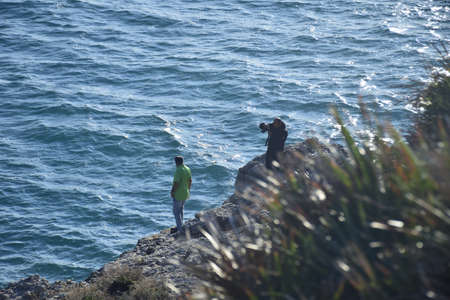 Salou, Spain - November 13, 2019: Men are photographed against the background of the coast.