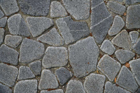 a fragment of a city wall made of natural stone of various colors and texturesの写真素材