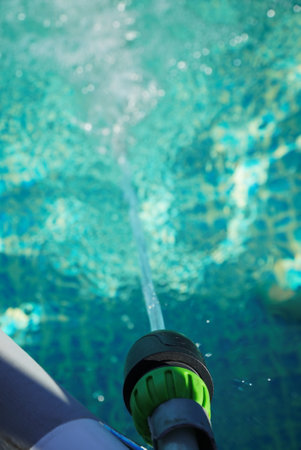 Water pours from a hose into a small round pool.の写真素材