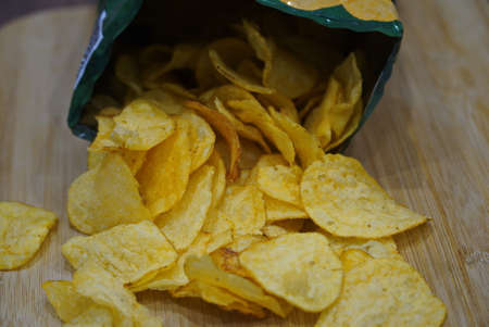 potato chips in an open bag on a wooden table.