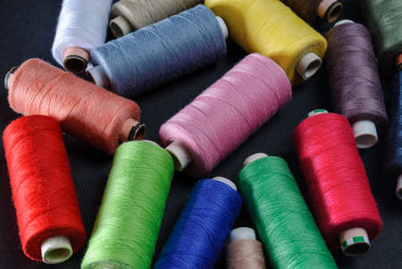 colorful spools of thread on black background