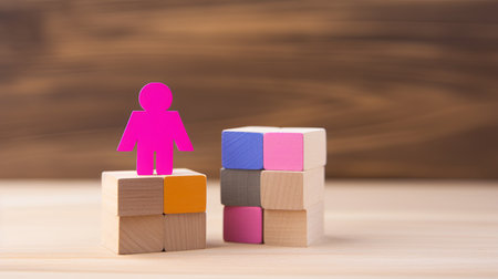 Colorful wooden blocks with pink man figure standing on them. Wooden backgroundの素材