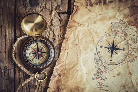 A compass and a map are placed on a piece of paper, showcasing navigation tools for exploring and finding directions in various terrains. The compass needle points north, aligning with the maps orientation.の素材